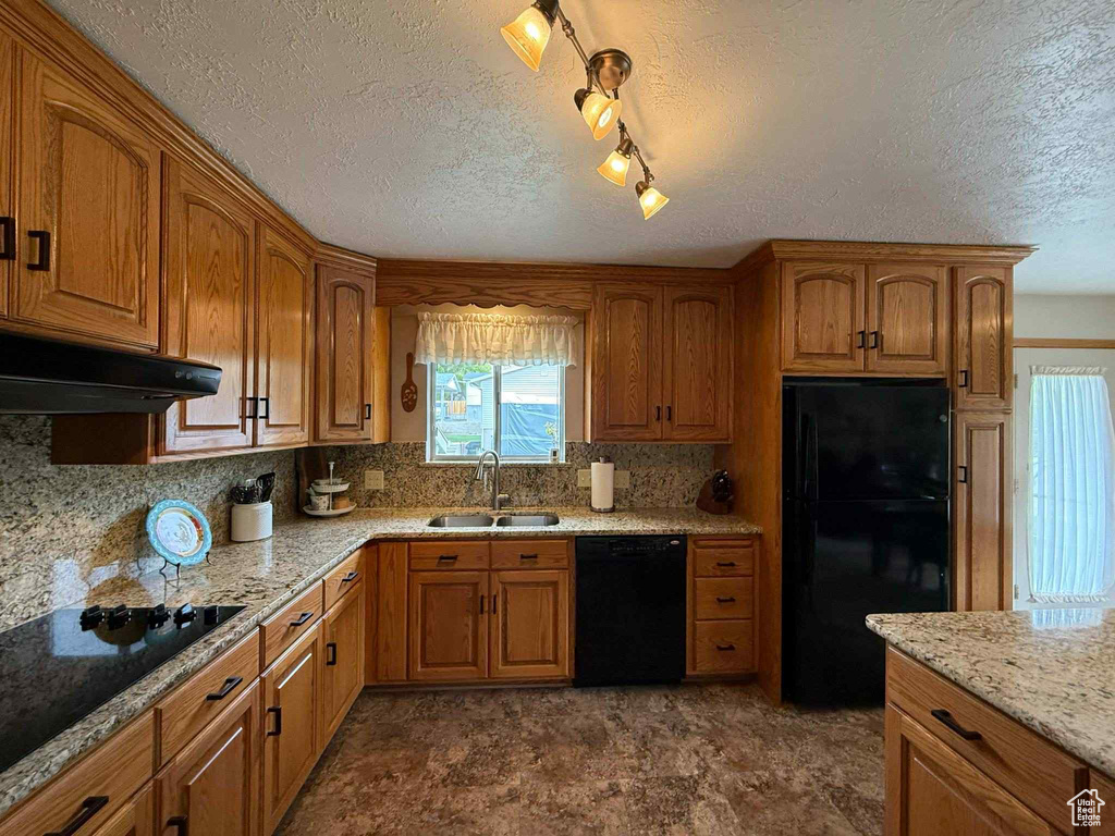 Kitchen with black appliances, a sink, plenty of natural light, tasteful backsplash, and a textured ceiling