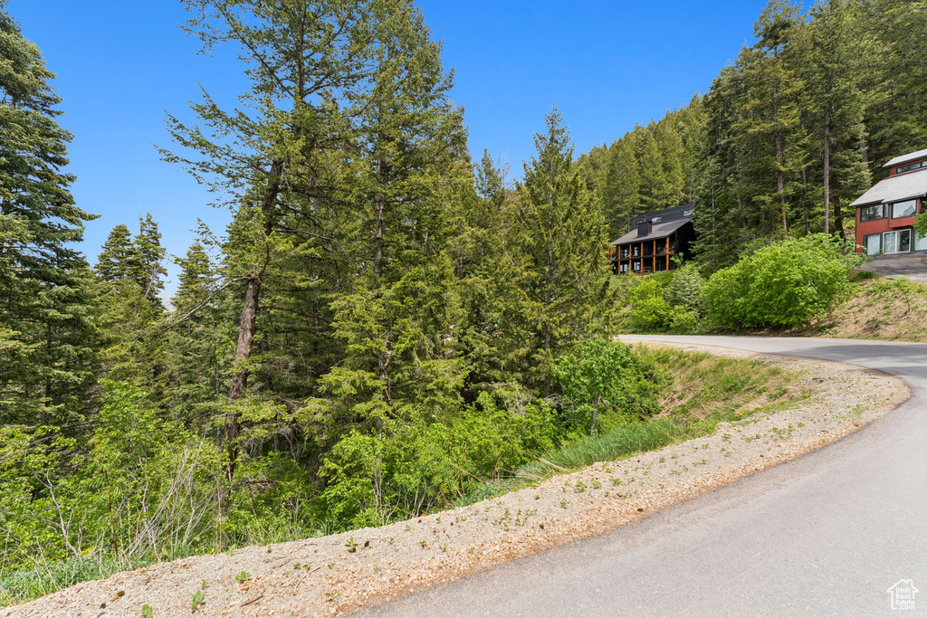 View of asphalt driveway featuring a view of trees