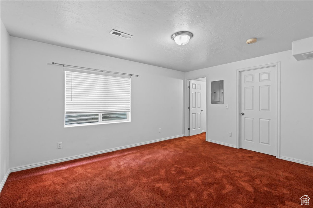 Unfurnished bedroom with carpet flooring, electric panel, baseboards, and a textured ceiling