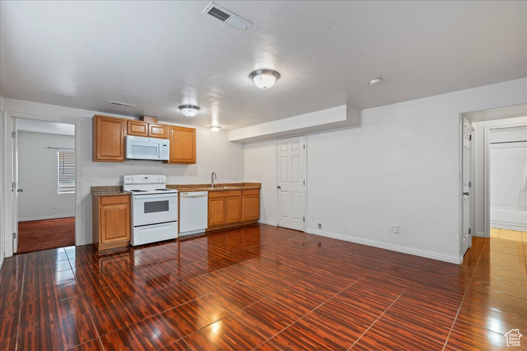Kitchen featuring white appliances, a sink, and baseboards