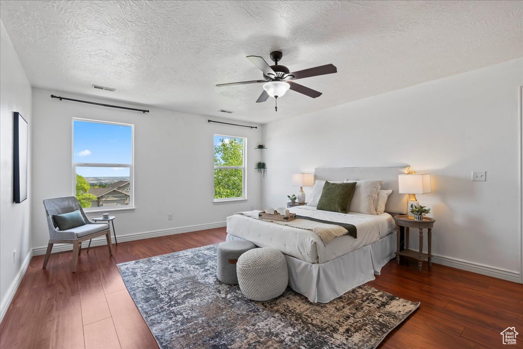 Bedroom with wood finished floors, baseboards, a textured ceiling, and ceiling fan