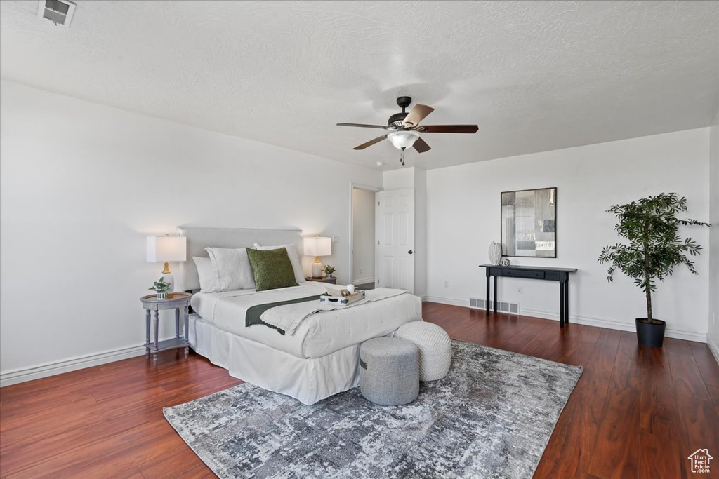 Bedroom with wood finished floors, baseboards, a textured ceiling, and a ceiling fan
