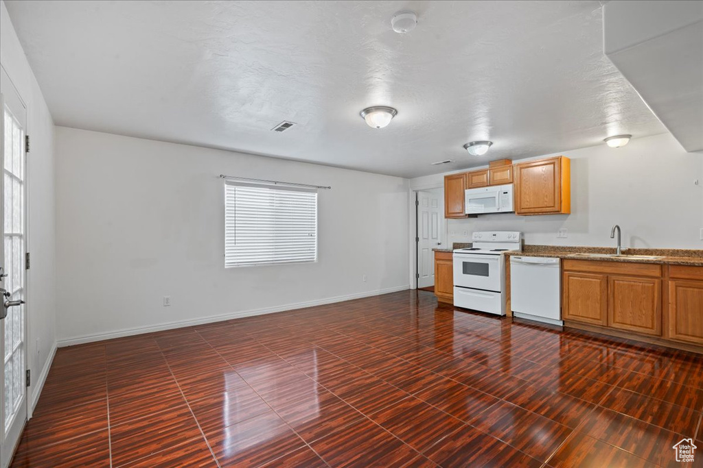 Kitchen featuring white appliances, a sink, plenty of natural light, and baseboards