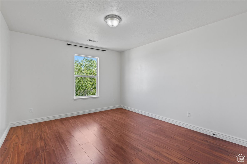 Empty room featuring wood finished floors, baseboards, and a textured ceiling