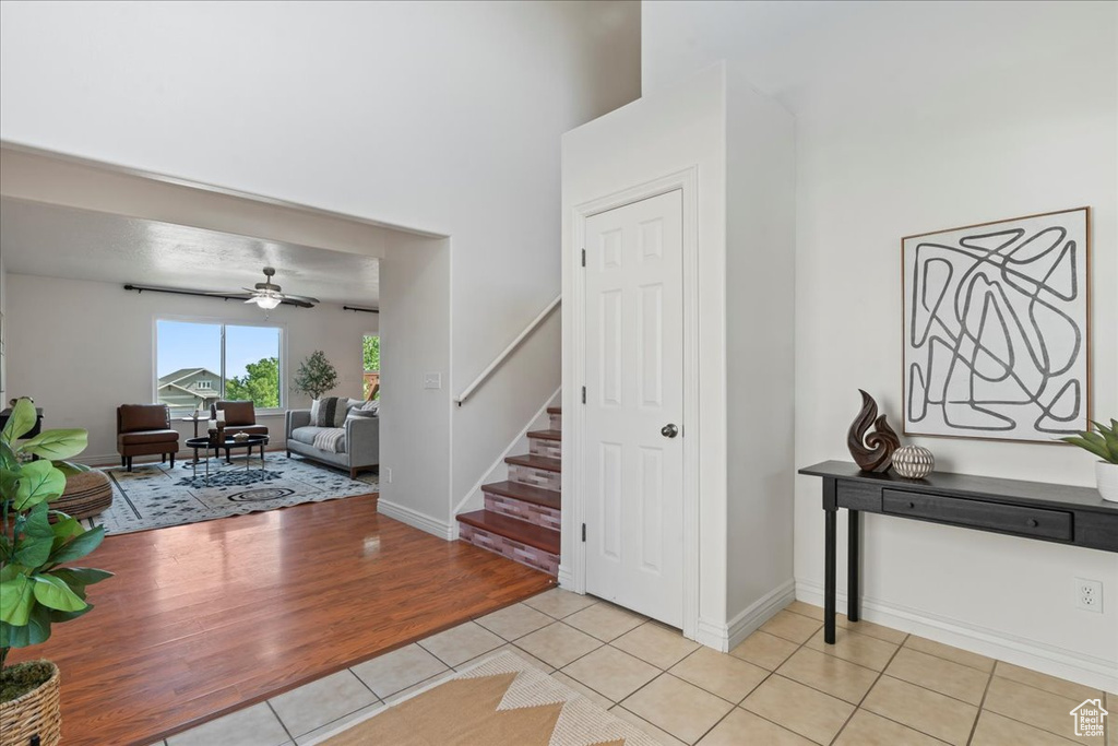 Foyer featuring stairway, light tile patterned floors, ceiling fan, and baseboards