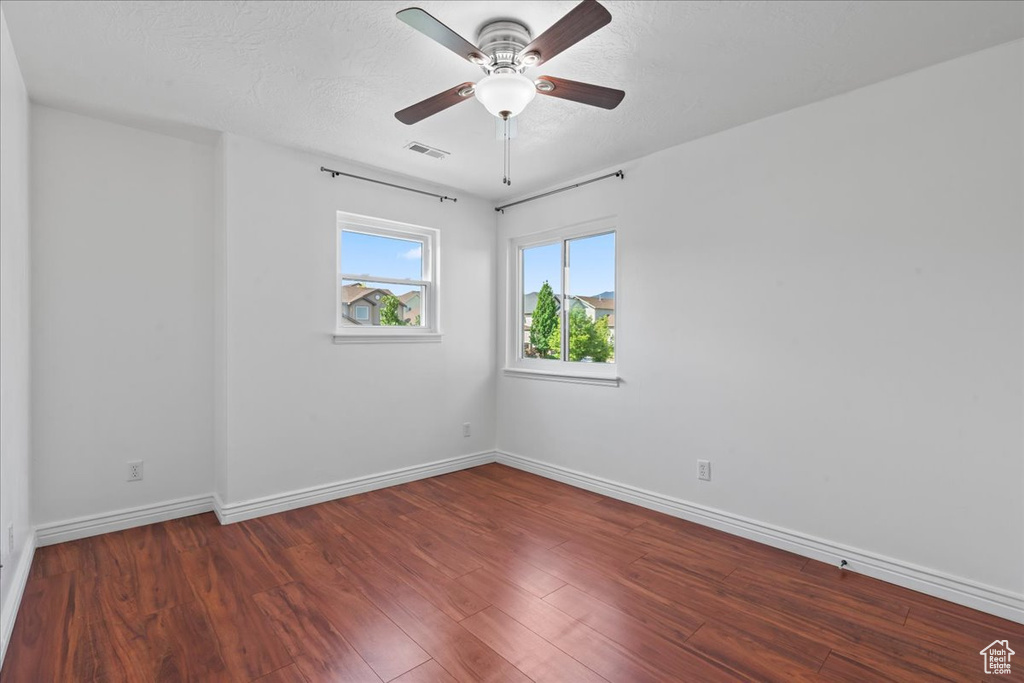 Spare room featuring wood finished floors, baseboards, and a ceiling fan