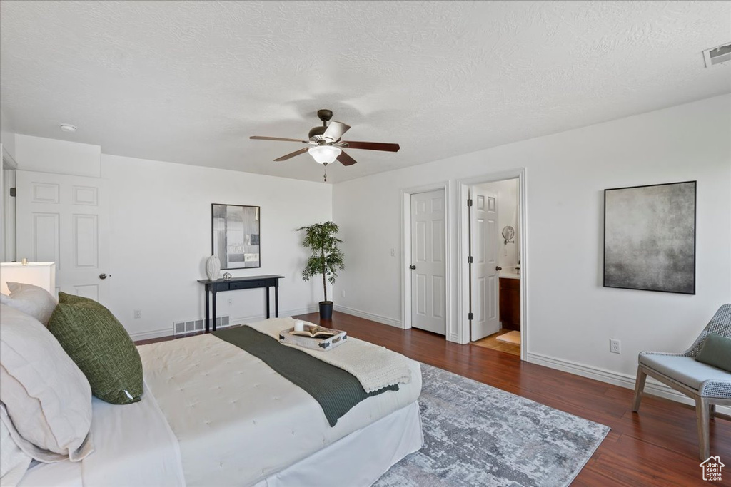 Bedroom with wood finished floors, baseboards, ceiling fan, a textured ceiling, and connected bathroom