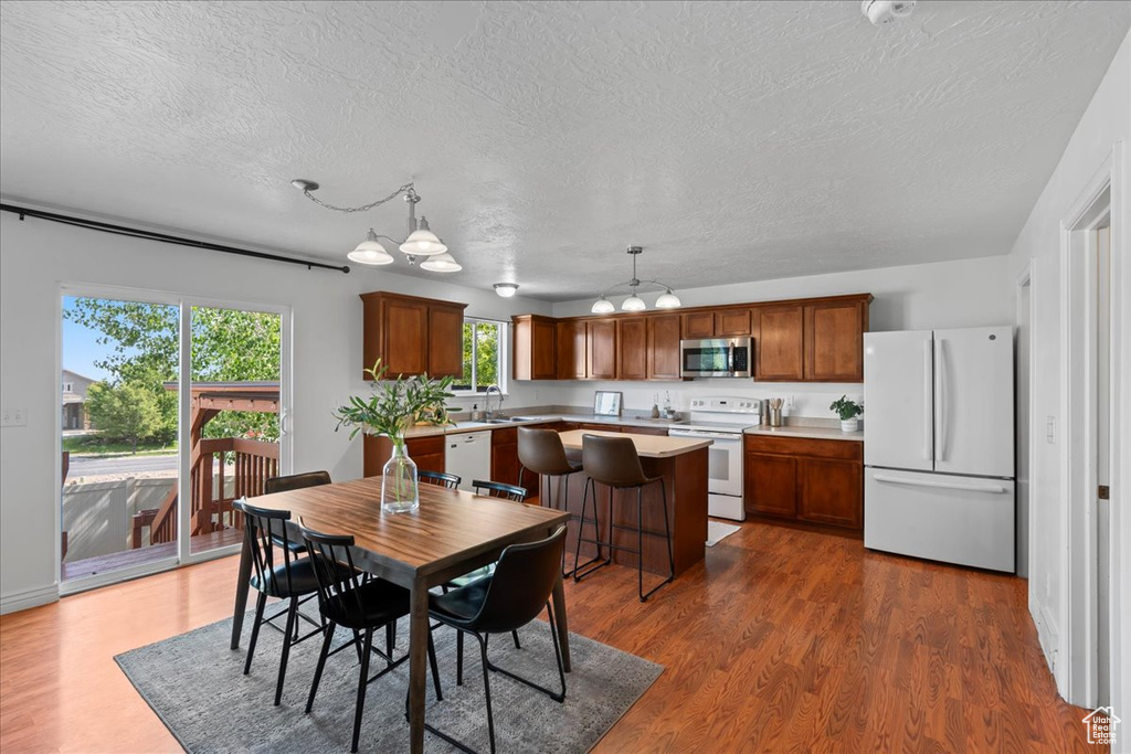 Dining area with a textured ceiling, dark wood-style flooring, and a chandelier