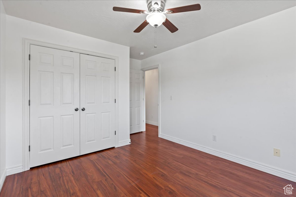 Unfurnished bedroom featuring baseboards, wood finished floors, a closet, and ceiling fan