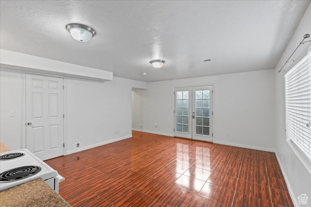 Unfurnished living room featuring baseboards and french doors