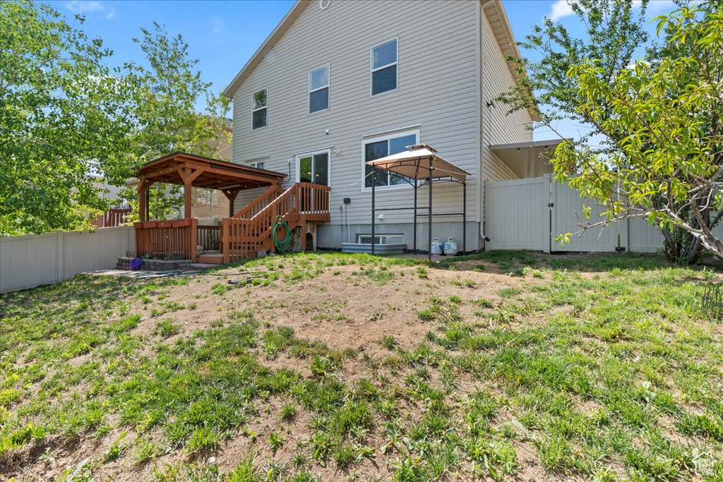 Rear view of house with a gazebo, a gate, and a fenced backyard