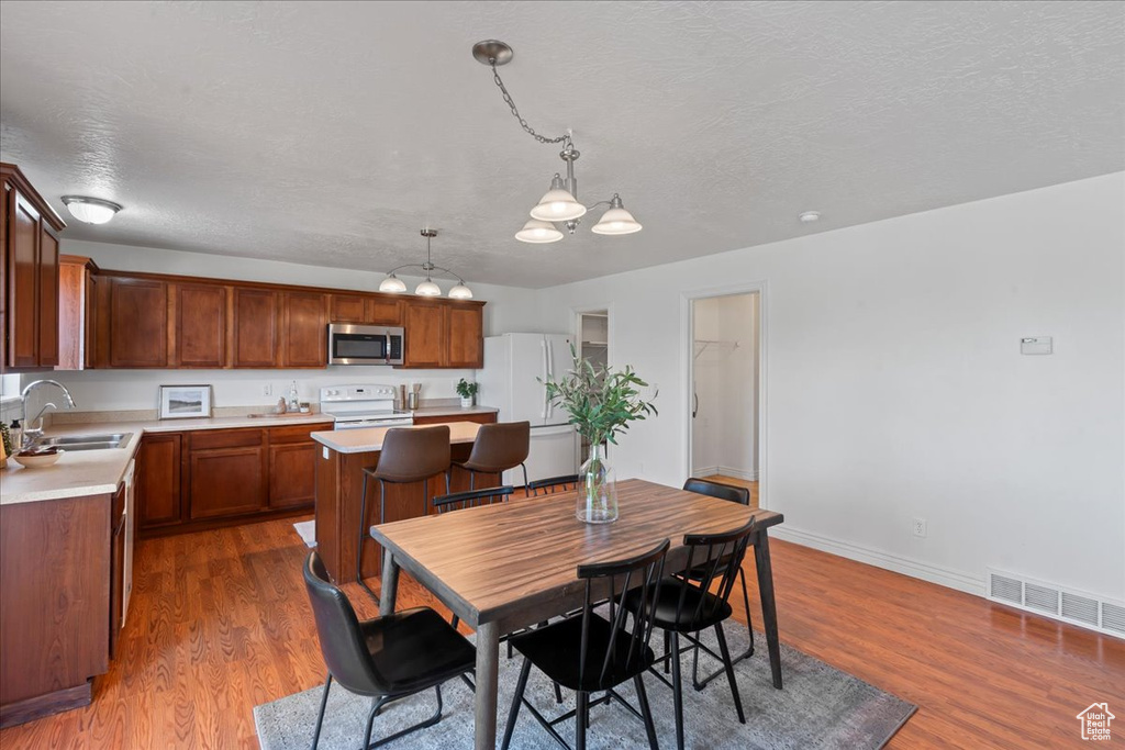 Dining space featuring dark wood-type flooring, a textured ceiling, baseboards, and a chandelier
