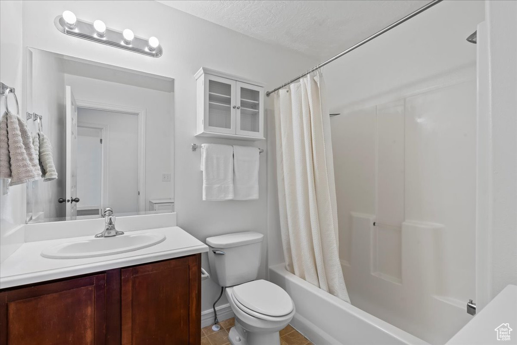 Bathroom with vanity, shower / bath combo, toilet, and tile patterned flooring