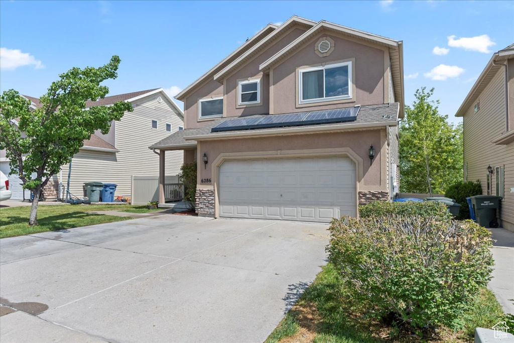 Traditional home featuring stucco siding, stone siding, driveway, and a garage