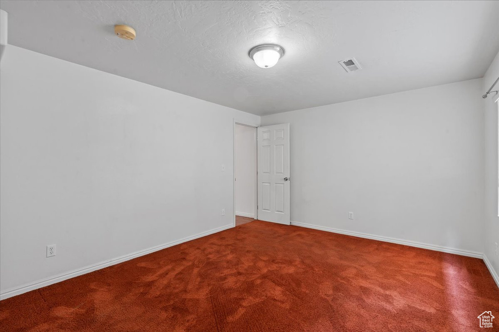Carpeted spare room featuring a smoke detector, baseboards, and a textured ceiling
