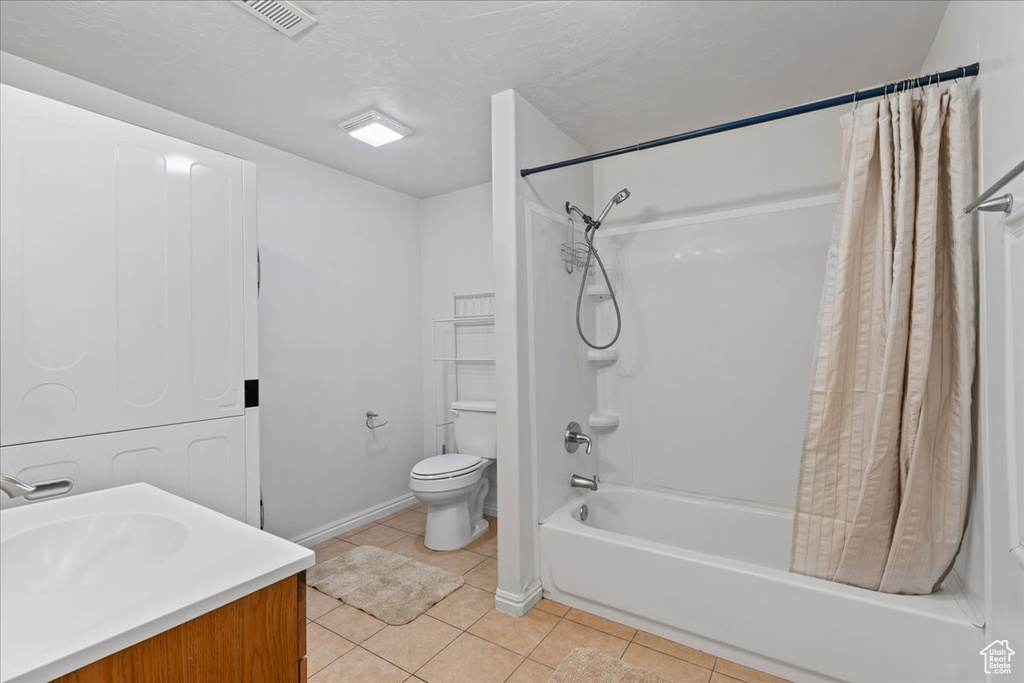 Bathroom featuring shower / bath combination with curtain, tile patterned flooring, toilet, and vanity