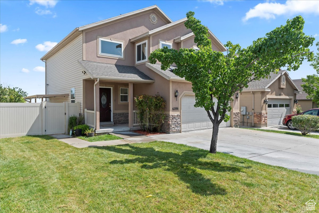 View of front facade featuring a gate, concrete driveway, stone siding, stucco siding, and an attached garage