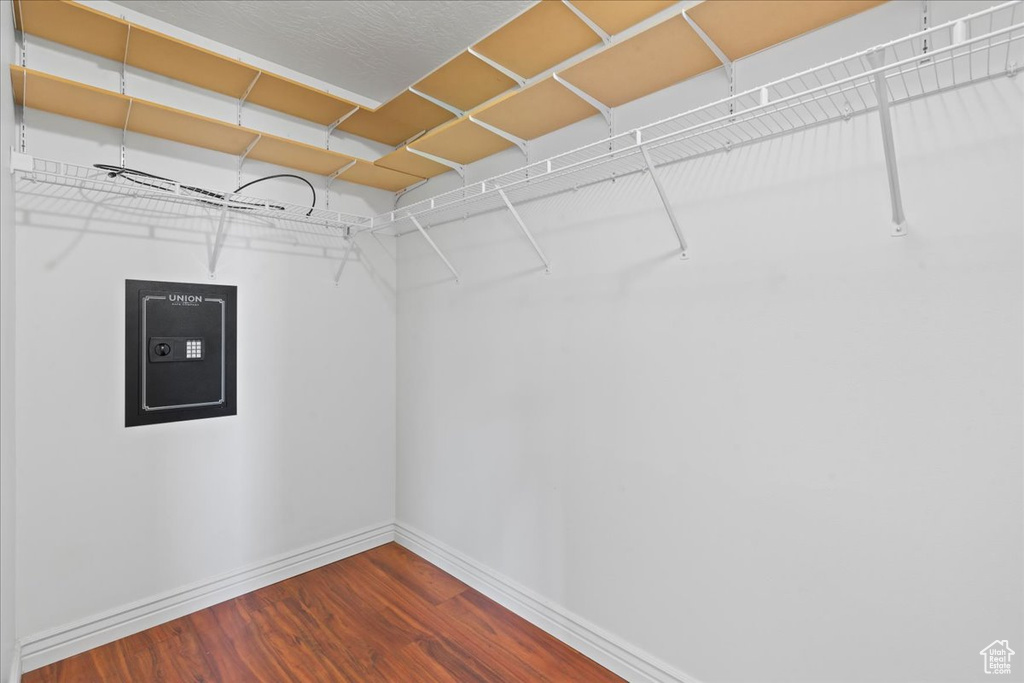 Walk in closet with dark wood-style flooring and electric panel