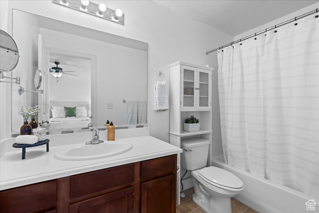 Ensuite bathroom featuring vanity, shower / bath combo, ceiling fan, toilet, and tile patterned flooring
