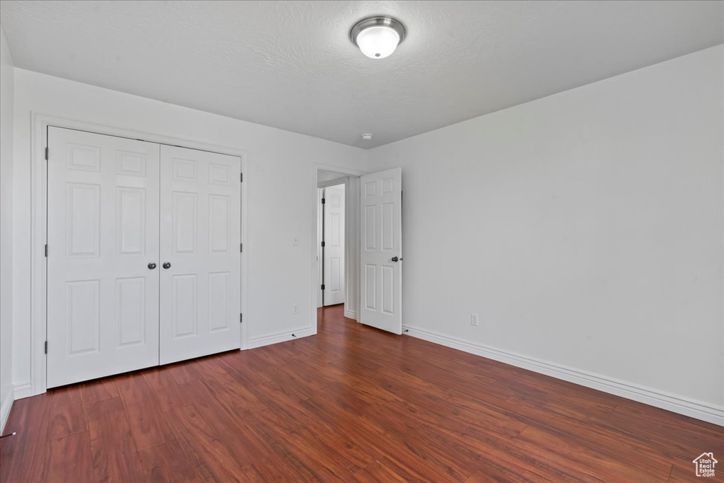 Unfurnished bedroom featuring baseboards, wood finished floors, and a closet