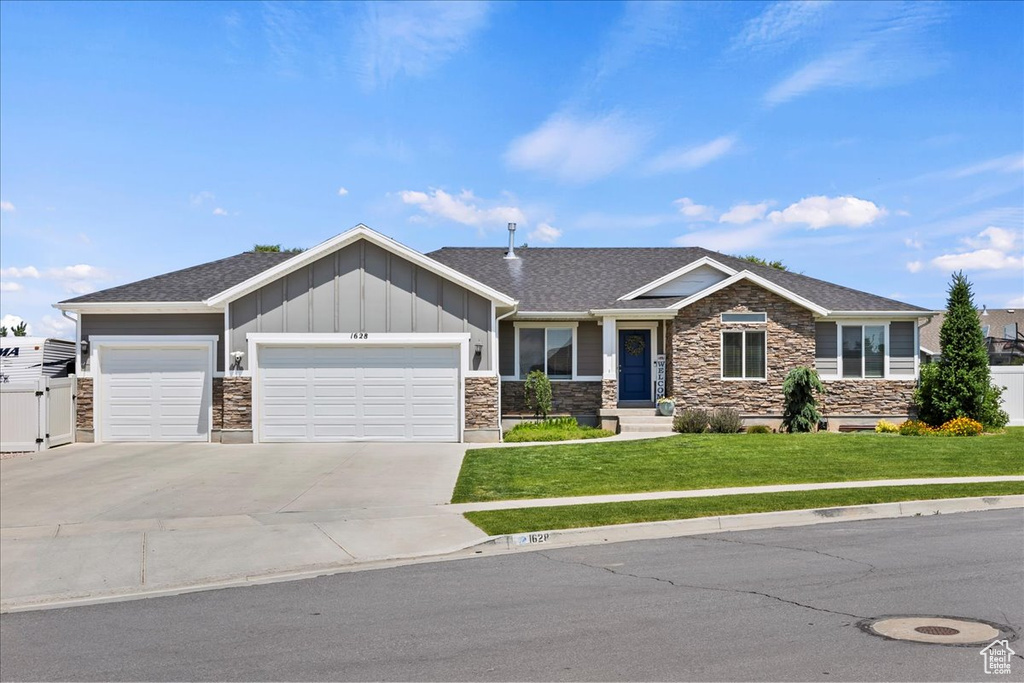 View of front of property featuring stone siding, a front lawn, an attached garage, board and batten siding, and concrete driveway