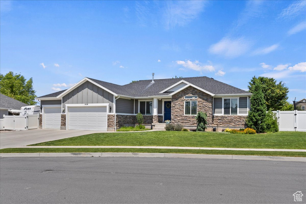 View of front of house featuring a gate, stone siding, a garage, and board and batten siding