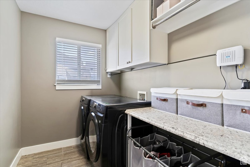 Laundry area with cabinet space, washing machine and dryer, baseboards, and light wood-style floors