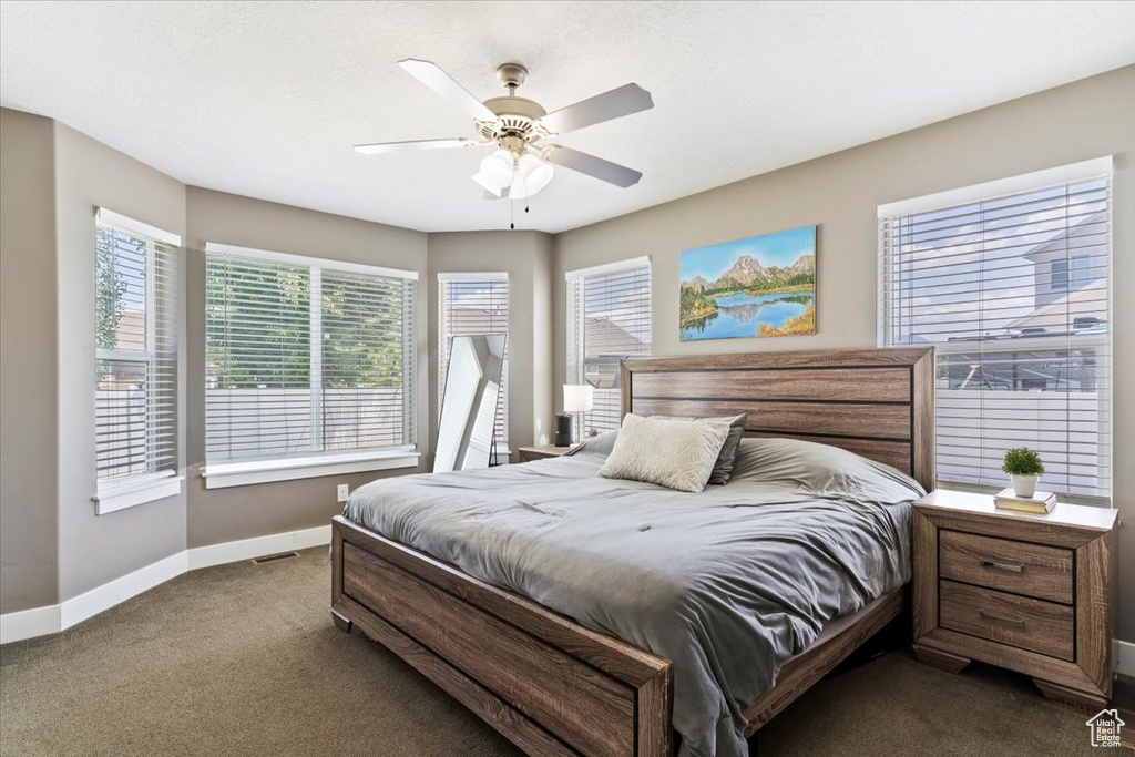 Bedroom with dark carpet, baseboards, and ceiling fan