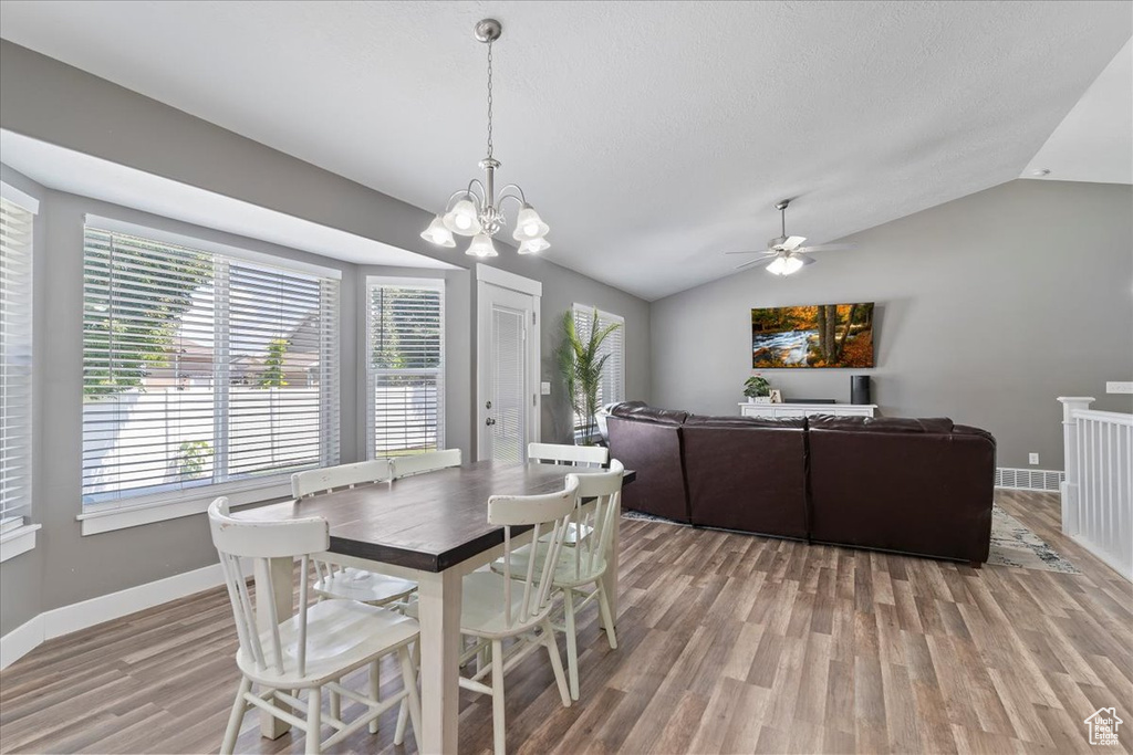 Dining space with light wood-style floors, lofted ceiling, baseboards, ceiling fan, and a chandelier