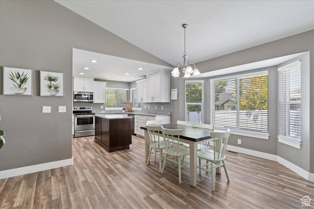 Dining space with light wood-style flooring, vaulted ceiling, baseboards, a chandelier, and recessed lighting