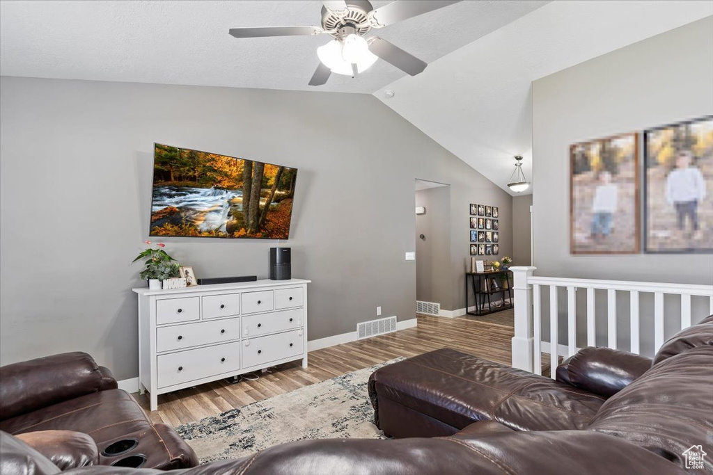 Living area with lofted ceiling, light wood-style floors, ceiling fan, and baseboards