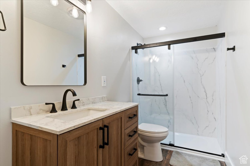 Full bath featuring vanity, a marble finish shower, and toilet