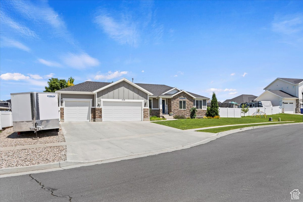 View of front of property with board and batten siding, an attached garage, a residential view, concrete driveway, and stone siding