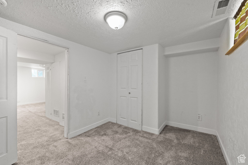 Unfurnished bedroom featuring carpet, a textured ceiling, a closet, and baseboards