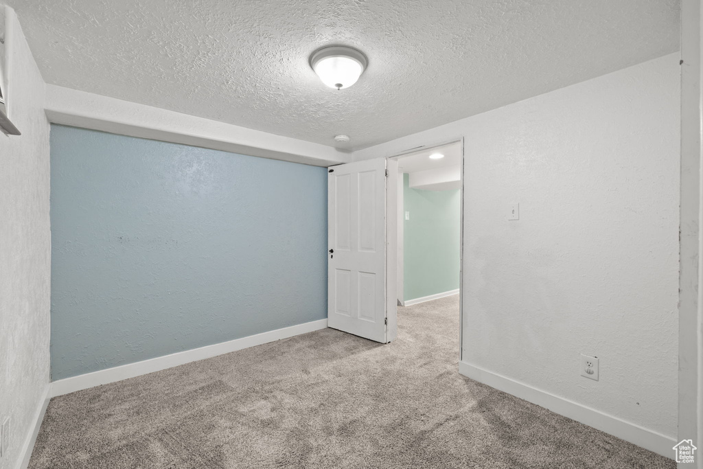Spare room with a textured ceiling, carpet, and baseboards