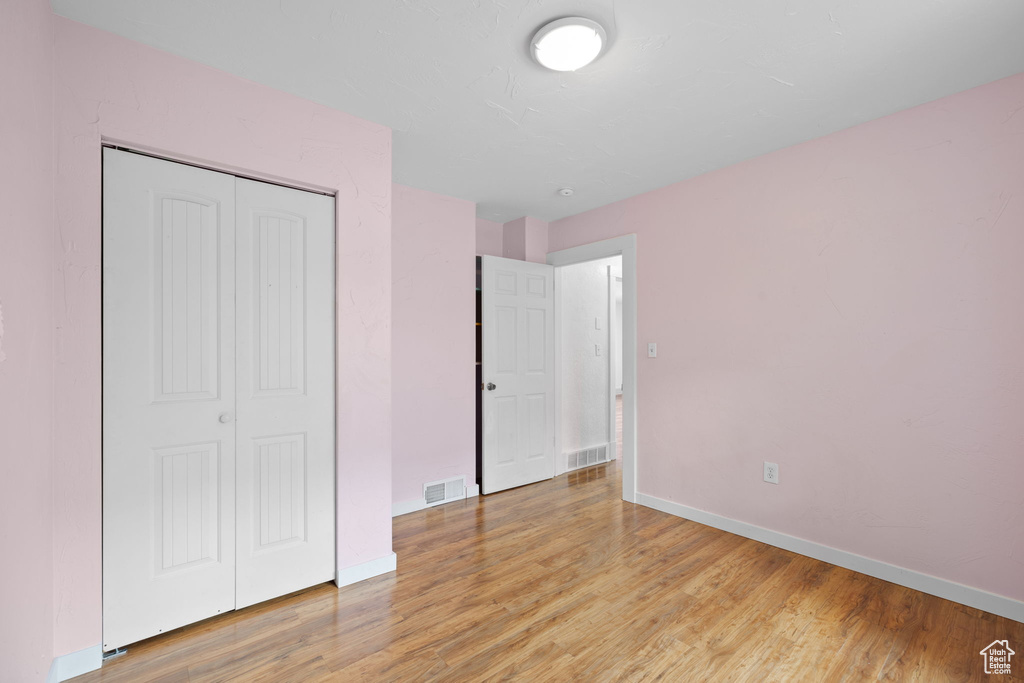 Unfurnished bedroom with light wood finished floors, baseboards, and a closet