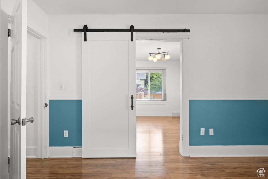 Unfurnished room featuring a barn door, wood finished floors, and baseboards