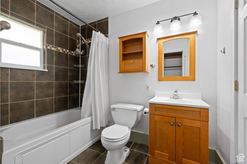 Bathroom with vanity, toilet, shower / tub combo, tile patterned floors, and baseboards