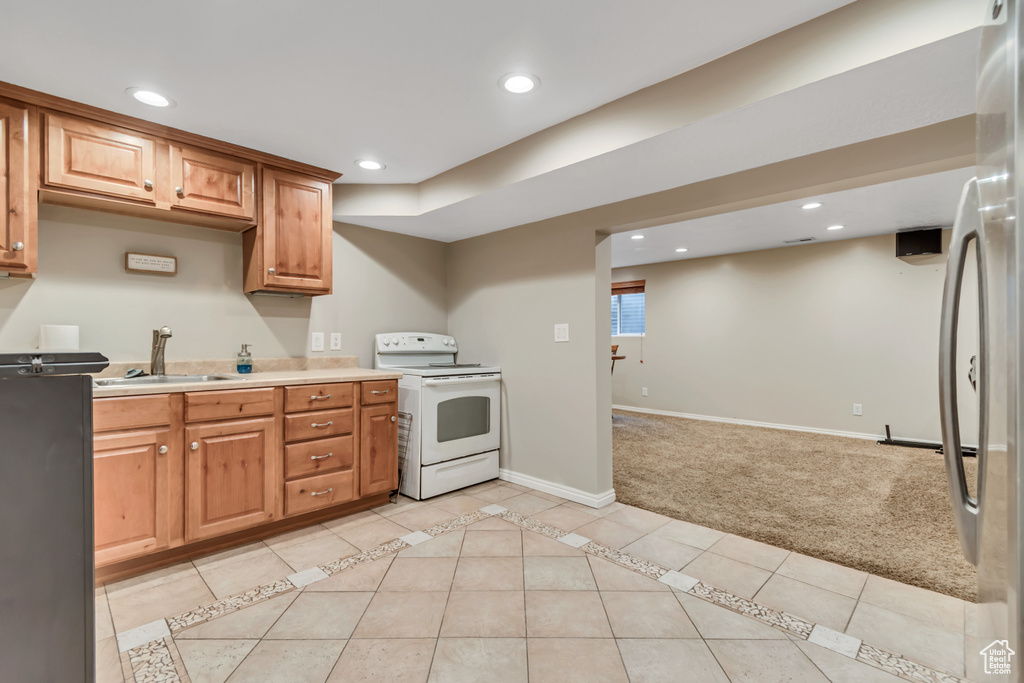Kitchen featuring electric stove, a sink, recessed lighting, light carpet, and light countertops
