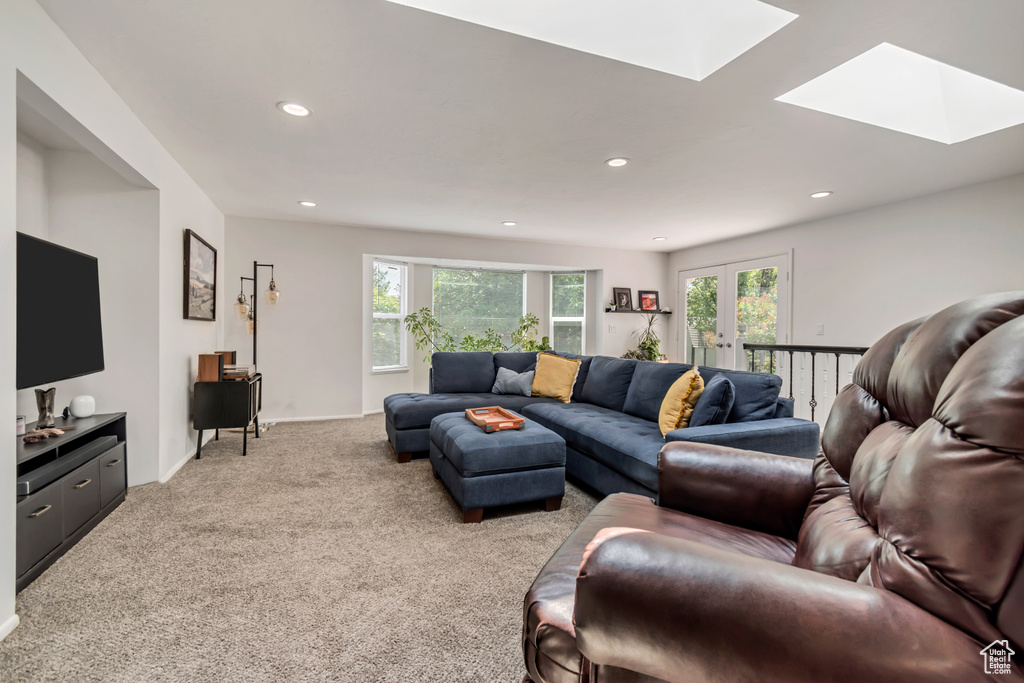 Living room featuring a skylight, light colored carpet, plenty of natural light, and recessed lighting