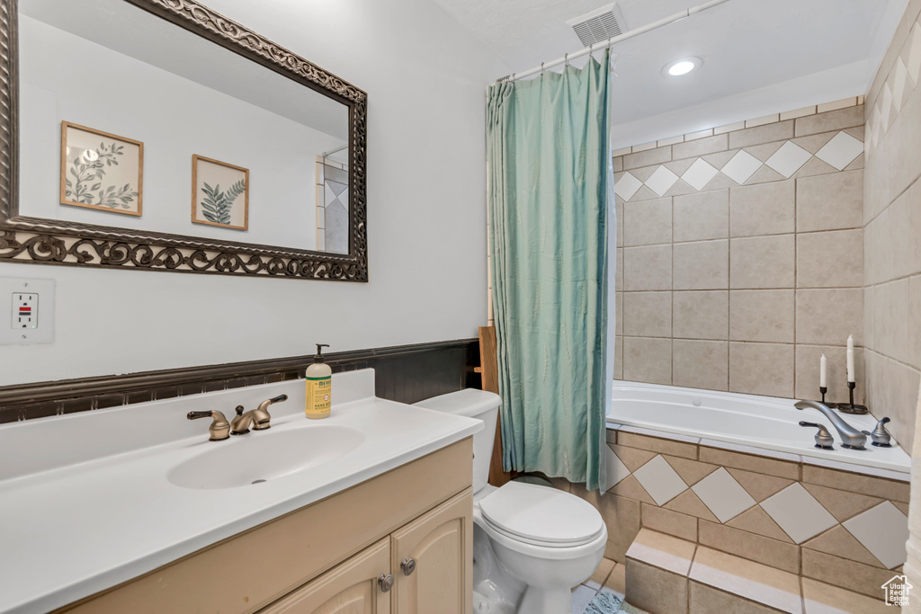 Bathroom with vanity, toilet, tiled shower / bath, and recessed lighting