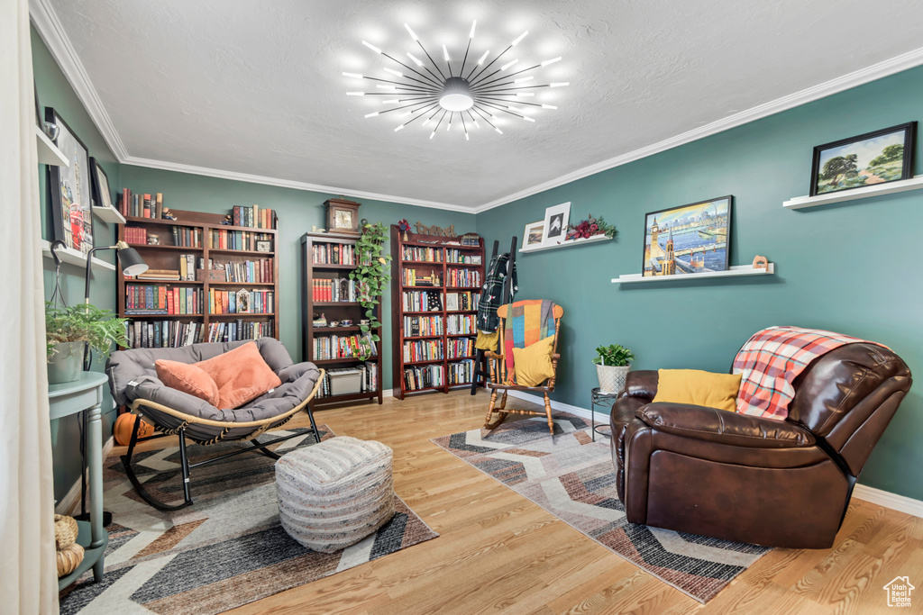 Sitting room with a chandelier, wood finished floors, ornamental molding, and baseboards