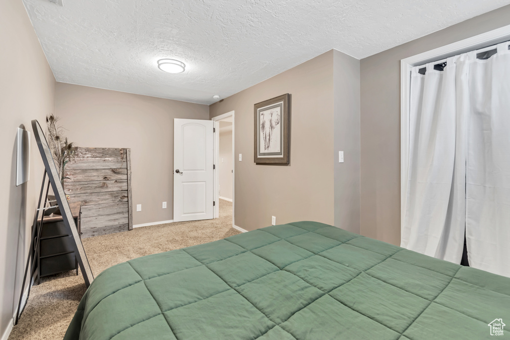 Carpeted bedroom featuring a textured ceiling and baseboards