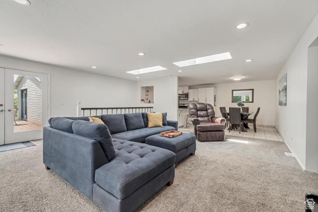 Living room featuring light carpet, a skylight, recessed lighting, healthy amount of natural light, and baseboards
