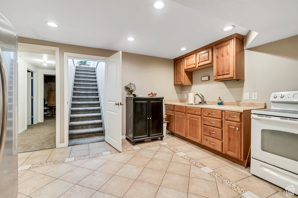 Kitchen featuring white electric range oven, a sink, recessed lighting, light countertops, and light tile patterned flooring