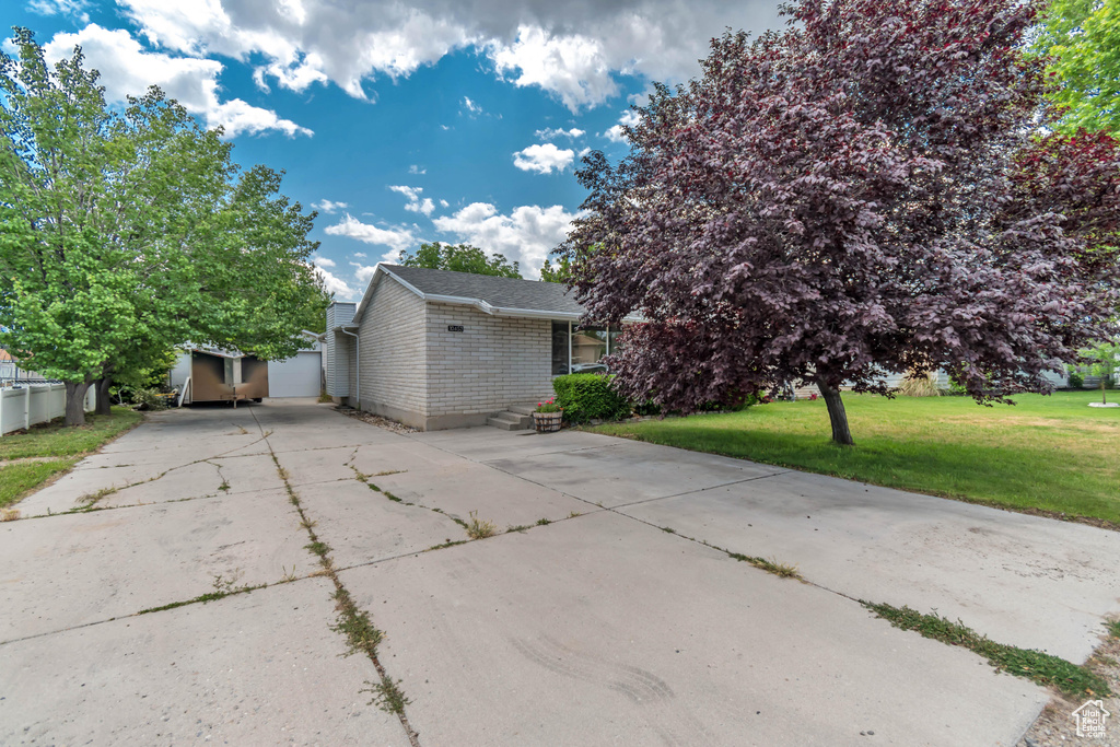 View of front of property with driveway, a front lawn, brick siding, and an outdoor structure