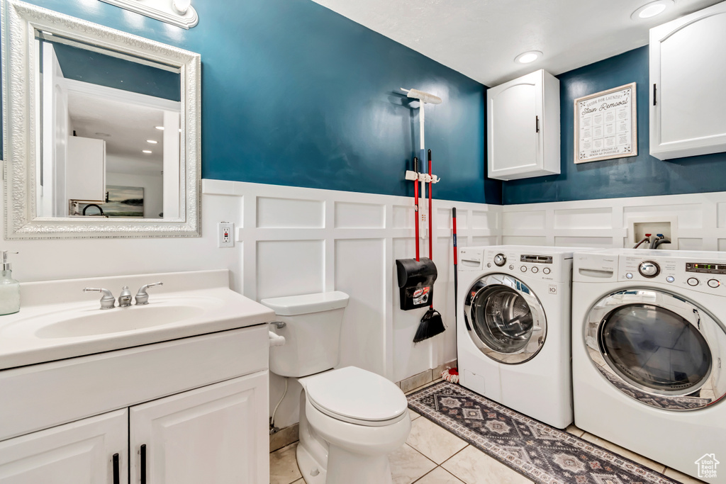 Bathroom with independent washer and dryer, a decorative wall, toilet, vanity, and wainscoting