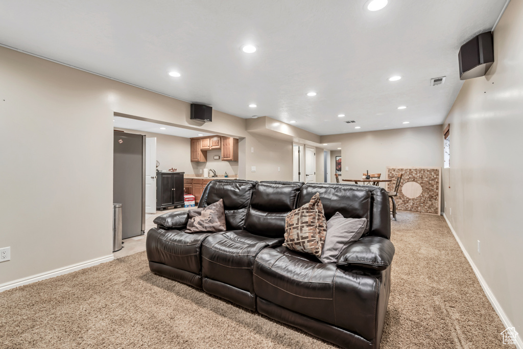 Home theater featuring bar with sink, light carpet, recessed lighting, and baseboards