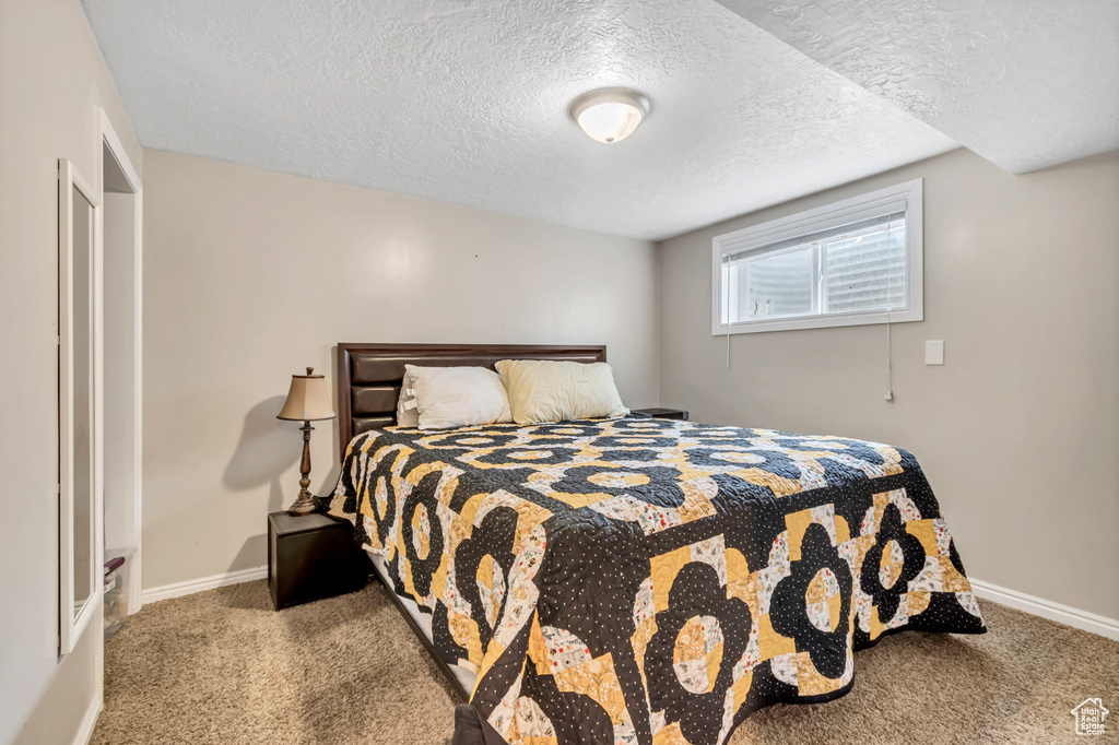 Carpeted bedroom featuring a textured ceiling and baseboards