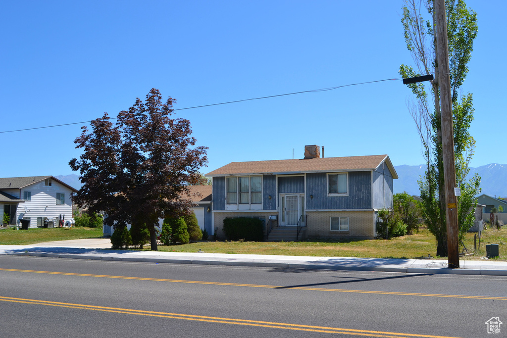 Split foyer home with brick siding, a chimney, and a front yard